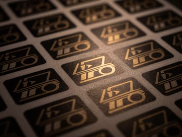 Close-up of a sheet of custom-cut stickers, matte finish, sharp graphics, low-key moody lighting, warm gold highlights, 35mm lens, scale-ready.