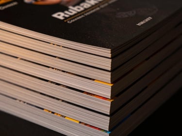 Close-up of a stack of premium brochures, crisp edges, vibrant colors, low-key moody lighting, warm gold highlights, 35mm lens, micrometer precision.