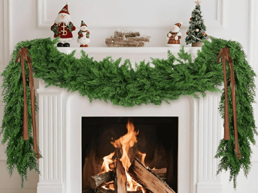 fireplace with green artificial garland and Christmas decorations