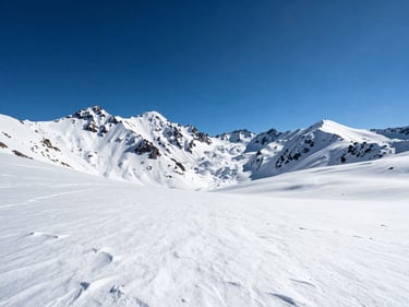 Panoramic high-altitude view from Valle Nevado, snow fields in the foreground, jagged Andean peaks receding into a cobalt sky, midday light, no people, vast scale