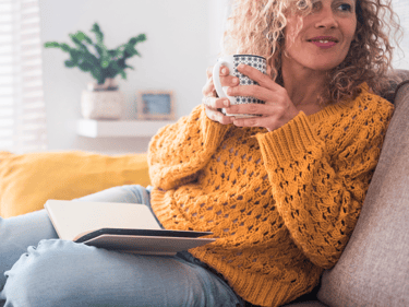 a woman sitting on a couch holding a coffee cup