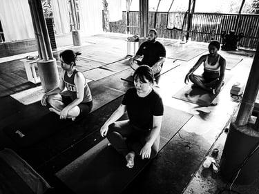 Students sit in Easy Pose at the start of a yoga class at The Bamboo Cottage Langkawi