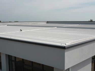Straight-on daylight photograph of a completed commercial building exterior showing the full roof structure — flat membrane roofing visible, parapet walls clean, equipment mounts installed, overcast sky above