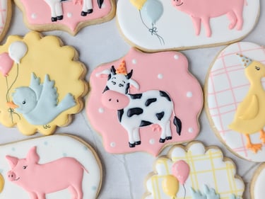 Cookies with cows, birds, pigs, and ducks in party hats in pink, white, blue, yellow