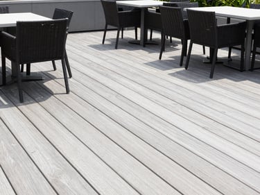 Clean wooden deck with patio furniture, bright daylight, professional editorial style.