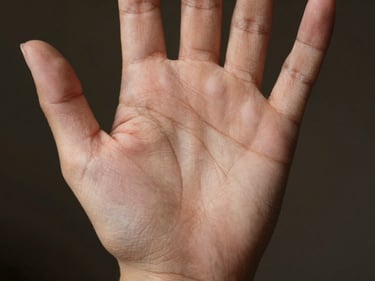 Close-up of a palm showing a vertical fate line rising from wrist toward middle finger, clinical window light, fine skin texture visible, neutral dark background, medium skin tone