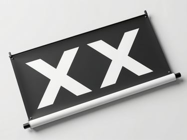 Overhead flat-lay of a printed rollup banner and X-banner leaning against a clean white wall, studio strobe lighting from above emphasizing the sharp graphic surface and material finish, tight crop showing banner top edge and stand hardware