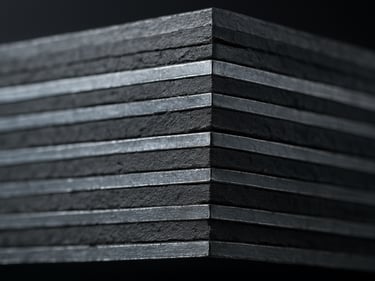 Extreme close-up of a laminated elastomeric bridge bearing showing alternating rubber and steel plate layers in cross-section, harsh site lighting revealing precise layer thickness, steel-gray tones