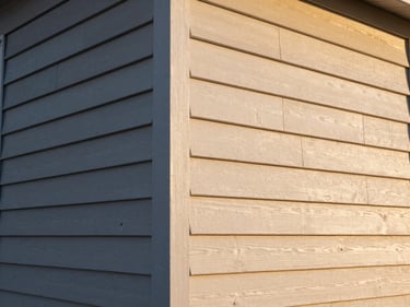 Exterior of a residential home with freshly painted siding and new trim detail, late-afternoon golden sidelight highlighting the texture of the painted wood lap siding