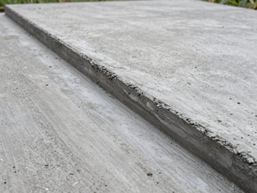 Freshly poured concrete driveway apron with a clean broom finish, north-facing diffused daylight showing the aggregate texture and crisp formed edges