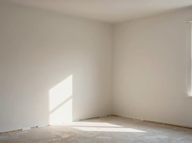 Interior room with freshly painted walls in a warm off-white, painter's tape removed to reveal a clean edge at the trim line, soft north window light across the flat surface