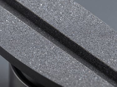Macro close-up of a resin bond diamond grinding wheel surface, fine grain texture visible under studio lighting, cool grey tones, sharp detail on bonding matrix