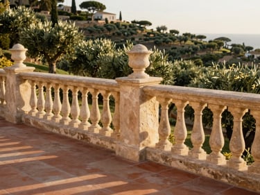Close-up architectural detail of a hillside villa terrace in Mijas Costa, stone balustrade, terracotta floor tiles, hillside olive grove visible in background, golden afternoon light