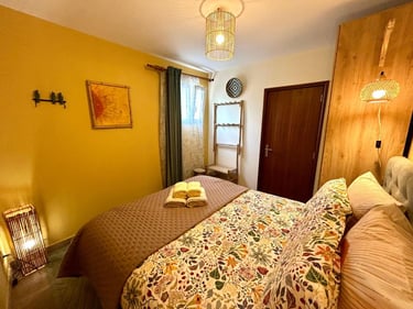 Cozy bedroom interior with a yellow accent wall, floral bedding, and warm bamboo lighting.