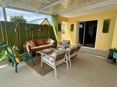 Modern outdoor patio furniture set on a covered terrace with colorful green and yellow walls.