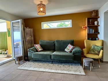 Bohemian living room with a green velvet sofa, mustard yellow accent wall, and woven pendant light.