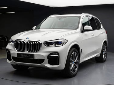 Front three-quarter angle of a white BMW X5 SUV under white showroom strobe lighting, dark background, chrome details sharp, no people