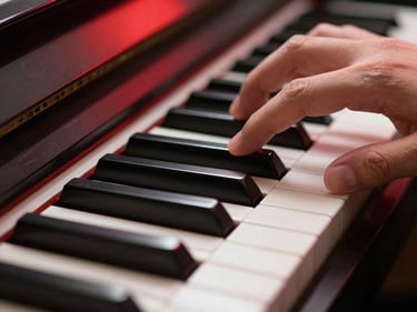 Macro close-up of fingers pressing black and white piano keys under sharp red studio lighting, high contrast.
