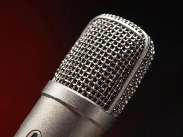 Studio microphone capsule close-up, metallic texture, dark background with subtle red recording glow.