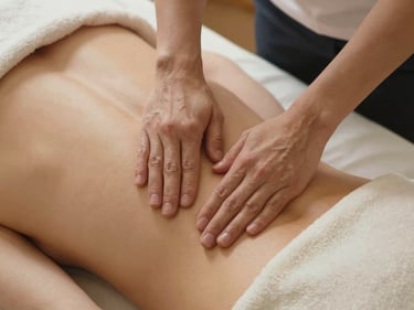 Overhead close-up of therapist palms gliding along a client's full back in long slow strokes, soft warm studio lighting, clean cream-colored treatment table linen visible