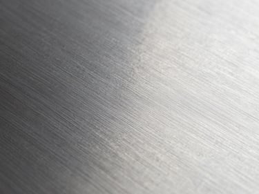 Macro close-up of stainless steel flat sheet surface, brushed 2B finish detail, cool studio lighting, no color cast, true metal tone, sharp grain texture visible