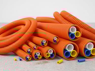 Bundled orange corrugated conduits containing colorful electrical microducts for fiber optic cable protection.