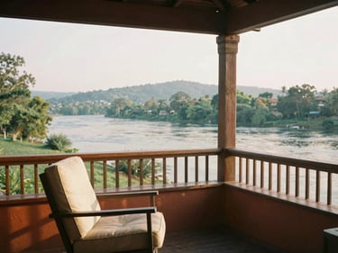 Riverside veranda with a comfortable chair, open views of the river and hills, warm morning light, warm editorial photography, 35mm film.