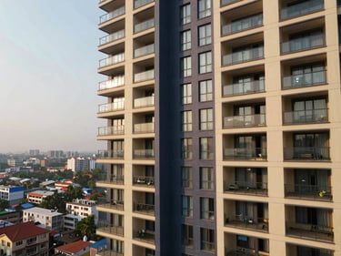 Sunlit high-rise apartment balcony with city views in India, contemporary design, warm natural daylight, deep navy and champagne accents, wide-angle lens