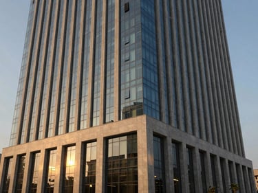 Modern commercial building exterior in an Indian urban setting, glass facade reflecting golden hour light, deep navy and champagne accents, architectural photography