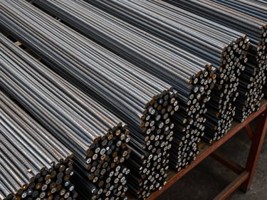 Bird's-eye view of bundled steel rebar stacked floor-to-ceiling on warehouse shelving, cool-white overhead lighting revealing grade stamp markings on each bar end, dense inventory framing