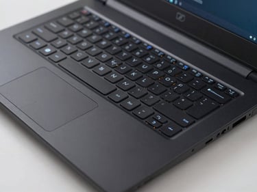 Close-up studio shot of a performance gaming laptop from above showing keyboard with subdued backlighting off, matte black chassis, even bright ambient lighting