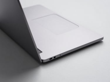 Top-down studio shot of an ultrabook laptop on a light gray surface, thin profile visible at the hinge, even shadowless studio lighting showing premium chassis