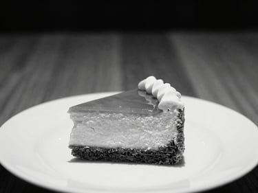 Close-up of a beautifully presented dessert on a minimalist plate, high-contrast monochrome, warm wood background, 35mm lens.