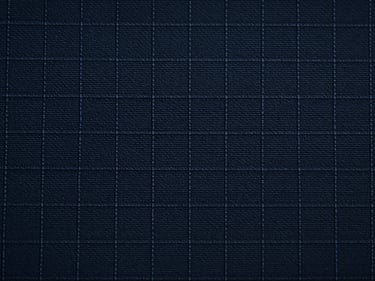 Macro flat-overhead close-up of ripstop technical textile under cool studio strobe, grid reinforcement weave pattern in sharp focus, dark navy tone, no garments