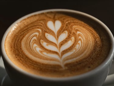 Close-up of latte art in a ceramic cup, warm golden hour light, shallow depth of field, moody editorial photography.