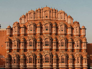 Wide environmental shot of Jaipur City Palace at golden hour, intricate sandstone arches, warm sunlight, no people