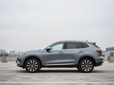 Wide three-quarter front profile of a gunmetal gray crossover SUV parked on an empty multi-level parking deck, clean overcast daylight, no people, minimal urban skyline visible in background