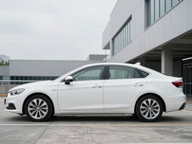 Wide three-quarter front profile of a clean white mid-size sedan parked on a smooth concrete surface in a modern urban parking structure, bright overcast daylight, no people