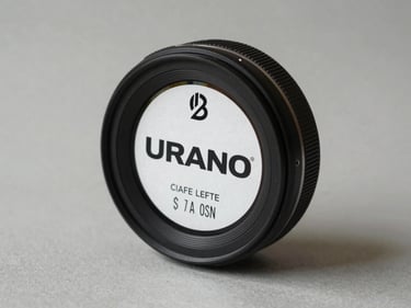 Close-up of a Urano commercial scale on a neutral light grey surface, product label visible, overhead retail lighting, no people