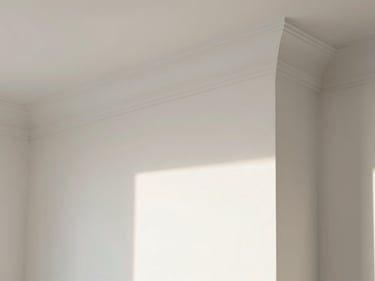 Close-up of a freshly painted white interior wall with crisp crown molding, bright natural light.