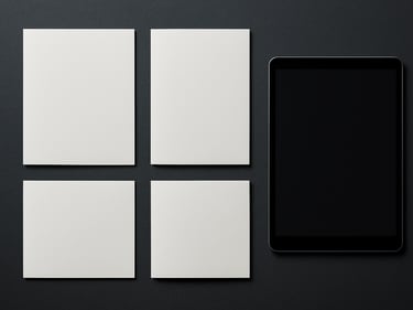 Product flat-lay of printed brochures and a digital display mockup side by side on a dark charcoal surface under even studio light, precise alignment