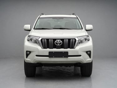 Head-on front-angle shot of a white Toyota Land Cruiser Prado on a clean grey studio floor, neutral temperature lighting, no people, badge and bumper detail crisp