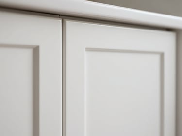 Kitchen cabinet door detail showing a flawless semi-gloss white finish, close-up of the edge and hinge area under neutral daylight, no brush marks or drips