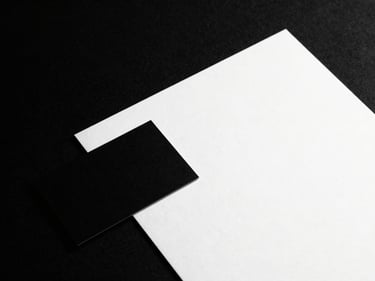 High-contrast, stark black and white studio shot of a minimalist business card and letterhead, crisp shadows, 50mm lens, premium editorial lookbook