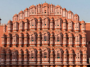 The intricate pink facade of Hawa Mahal in Jaipur, warm low-angle sunlight casting soft shadows, elegant composition, 35mm