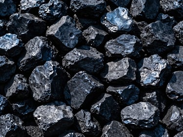 Close-up of glossy, black industrial coal lumps, stacked in a large pile, under dramatic, high-contrast lighting