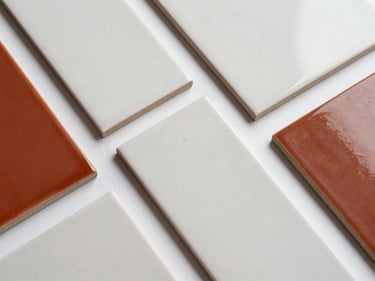 Overhead product flatlay of ceramic tile samples in pasta blanca and pasta roja finishes arranged on a white surface, studio strobe lighting, sharp material detail visible on each piece