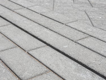 Close-up of interlocking concrete paving stones freshly laid on a Rive-Sud driveway, visible seam lines, fine sand in joints, overcast daylight showing surface texture and colour variation
