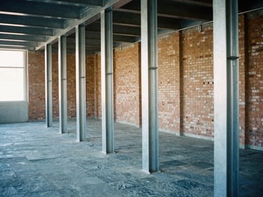 Industrial interior renovation with exposed brick and newly installed steel support columns, cool-toned 35mm film photography