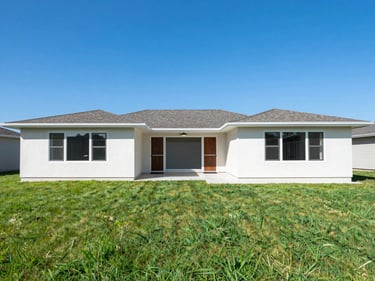 Real estate exterior with vibrant blue sky replacement and lush green grass enhancement, balanced daylight, wide-angle lens, natural saturated tones